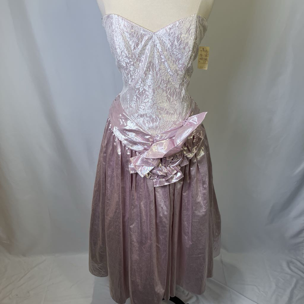 Mannequin wearing a pink and white dress with a floral detail on a plain background