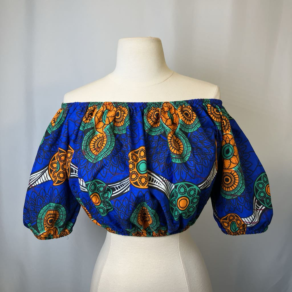 Colorful off-shoulder top on a mannequin against a plain background