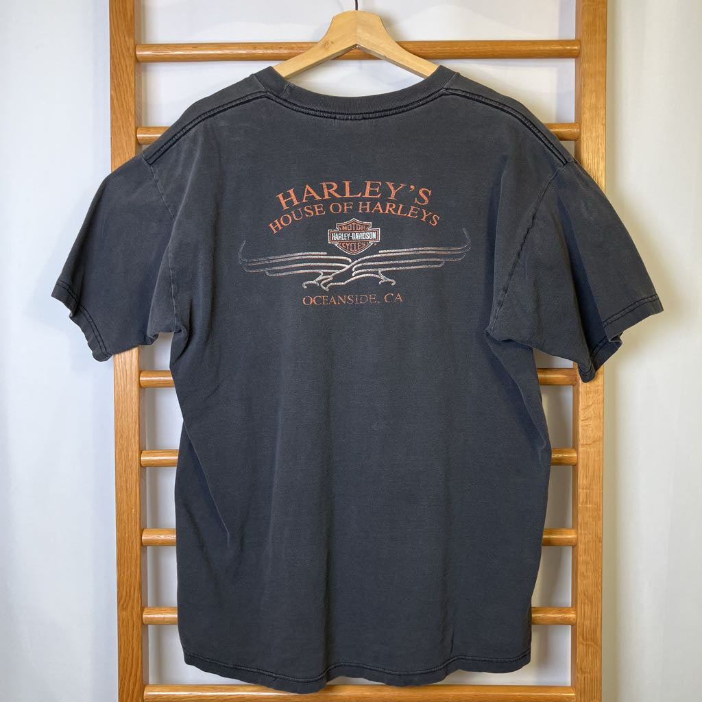 Black t-shirt with 'Harley's House of Harleys' logo on a wooden hanger against a white wall.