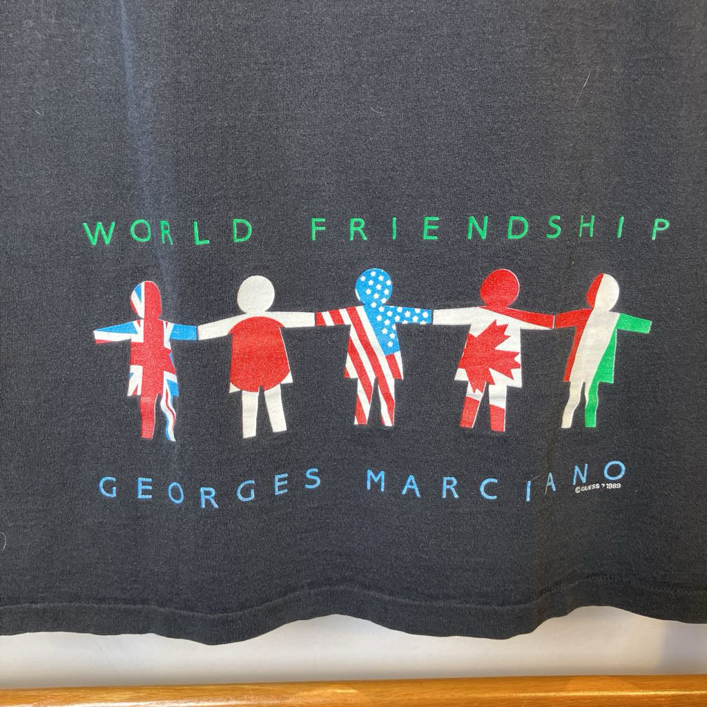 Dark gray t-shirt with 'World Friendship' design featuring international flags and 'Georges Marciano' branding.