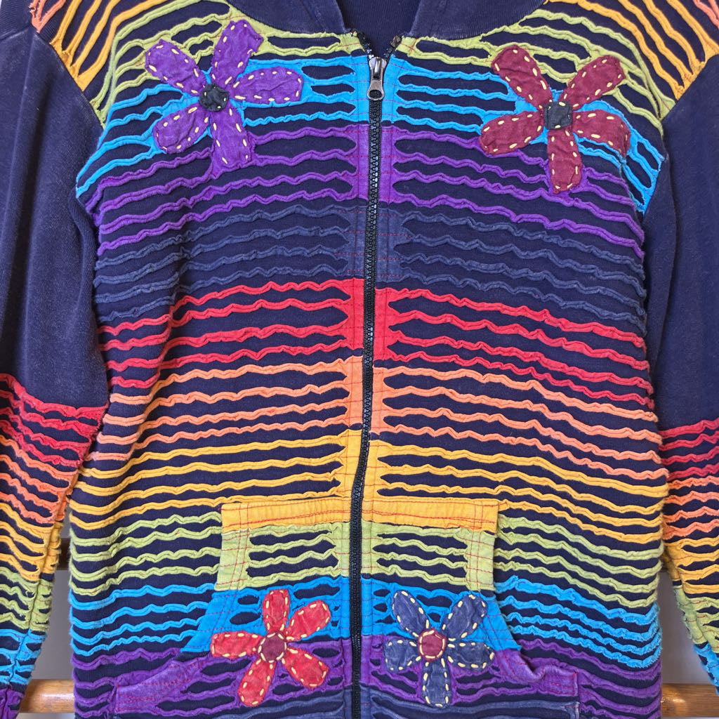 Colorful zip-up hoodie with floral designs on a wooden surface
