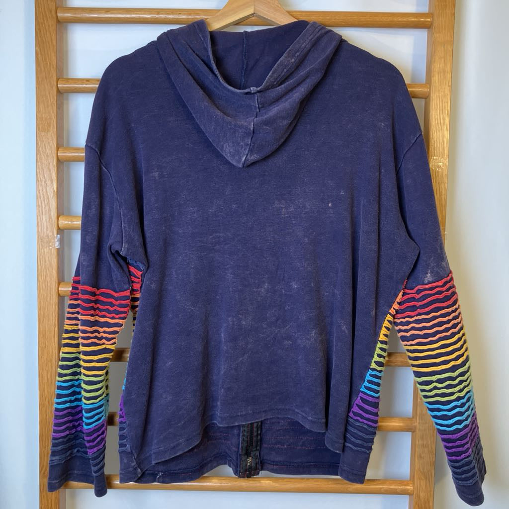 Blue hoodie with colorful sleeves on a wooden hanger against a white wall.