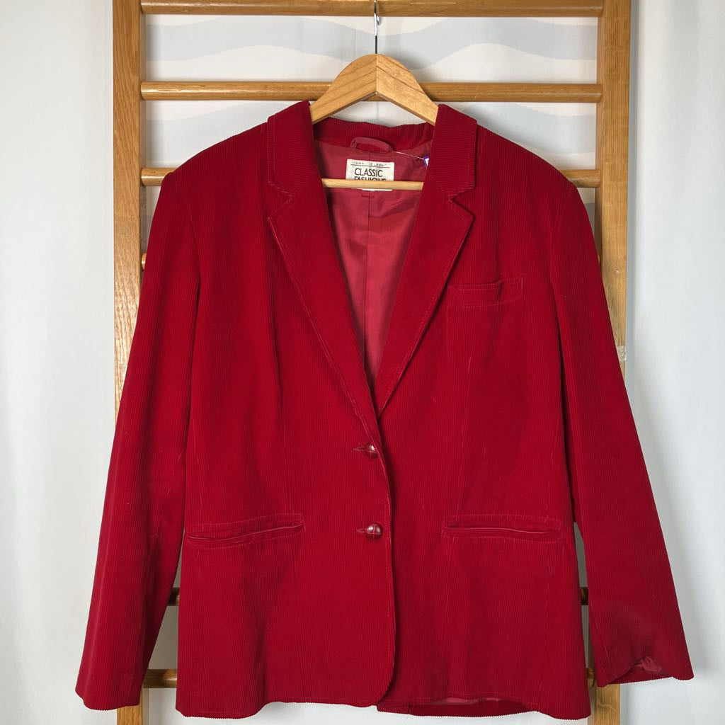 Red blazer on a hanger against a wooden panel background