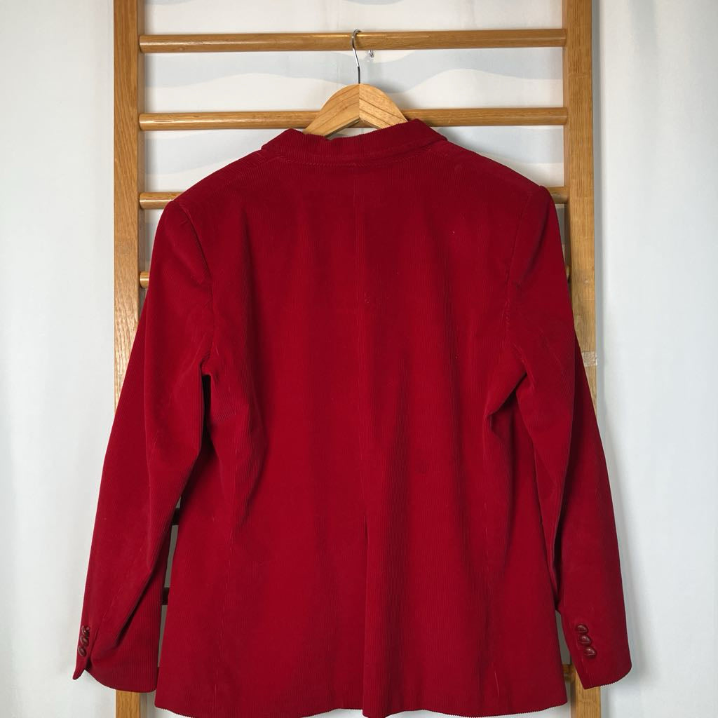 Red jacket on a wooden hanger against a white wall
