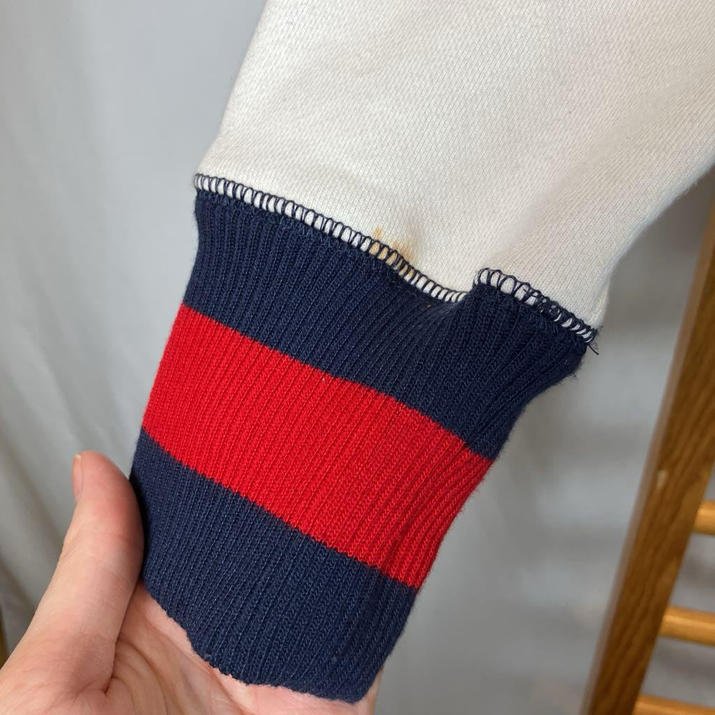 Close-up of a sweater sleeve with blue and red stripes held by a hand.