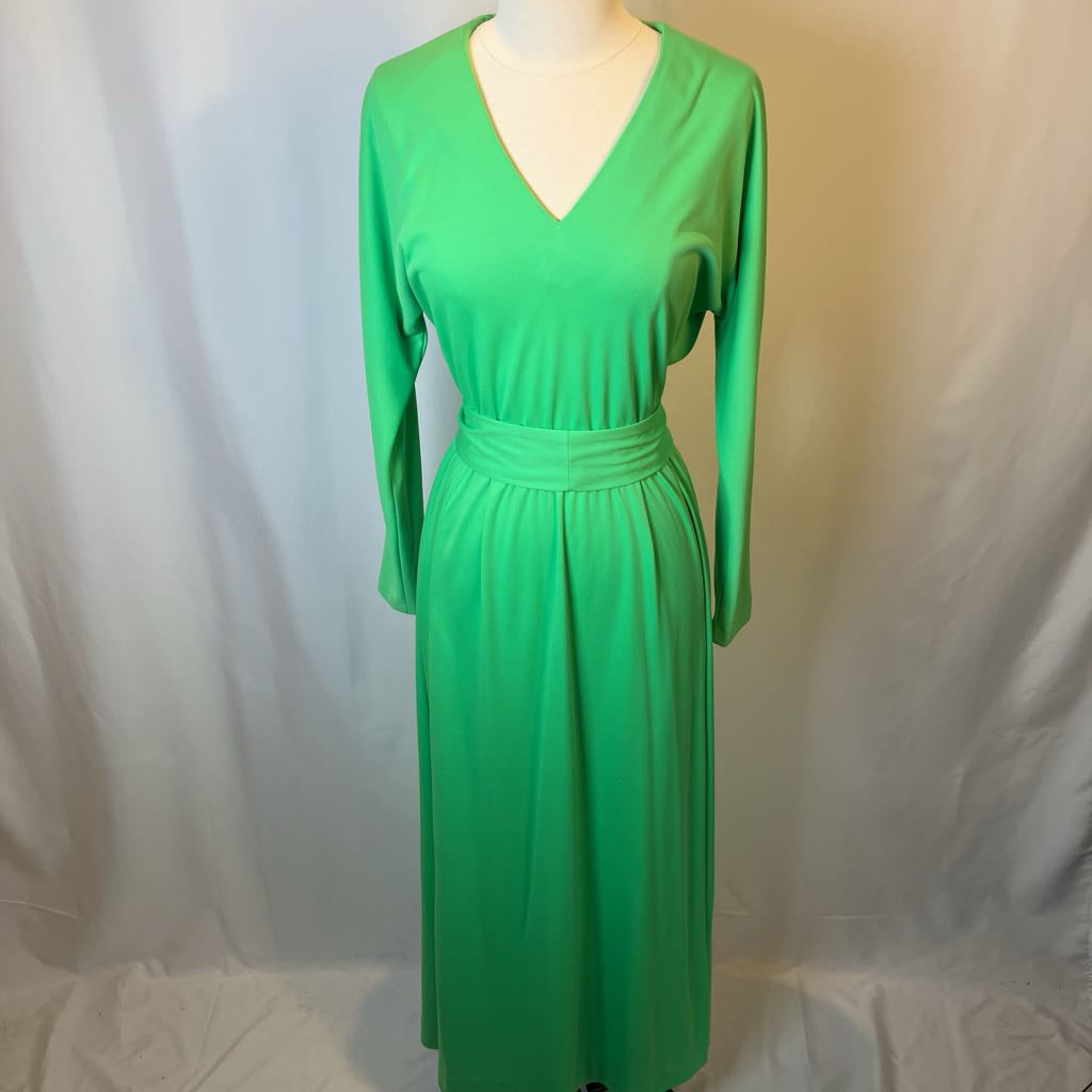 Green dress on a mannequin against a plain background