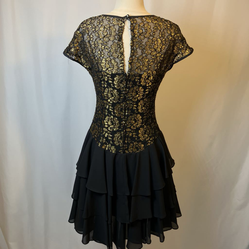 Black lace dress on a mannequin against a plain background