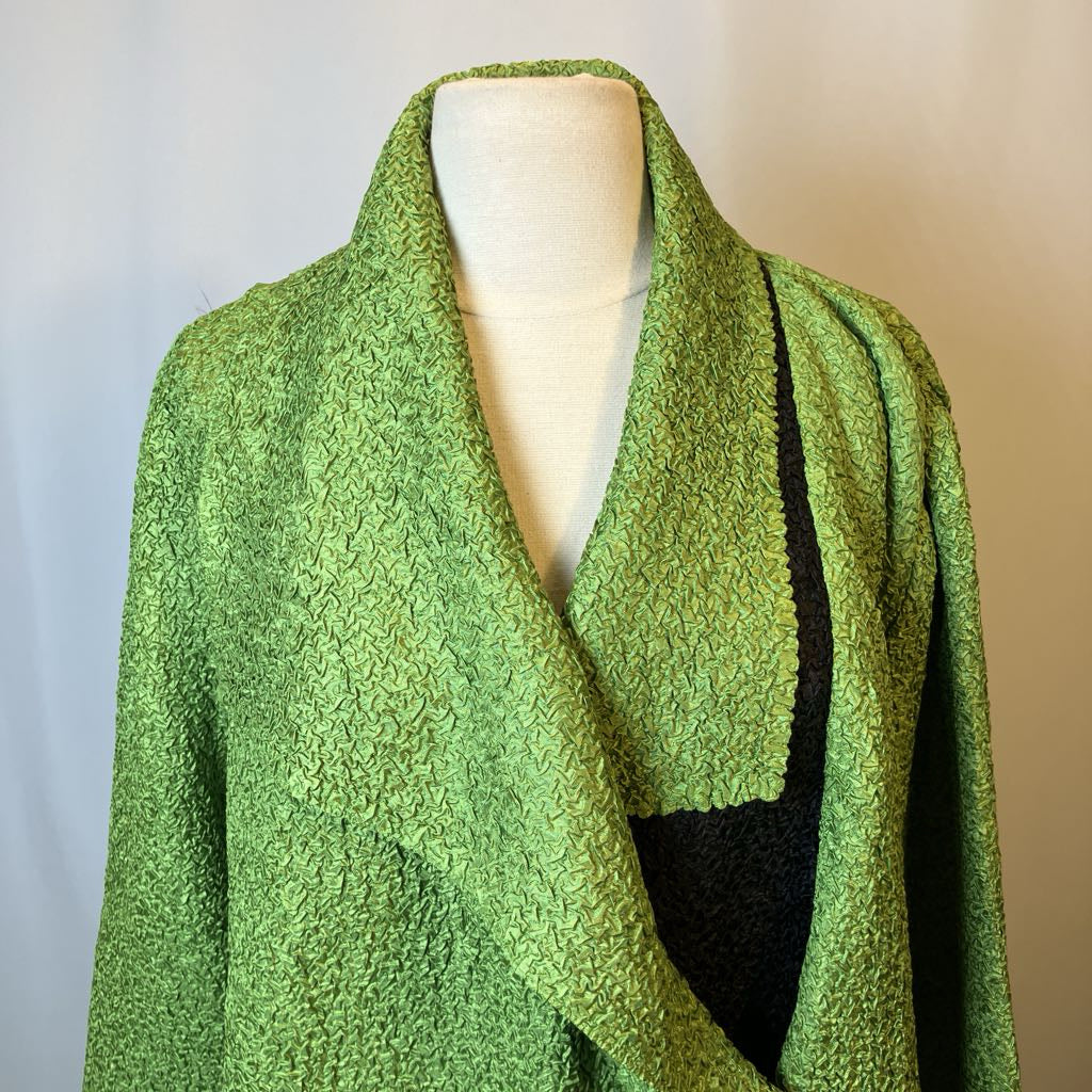 Green krinkled cardigan on a mannequin against a gradient background
