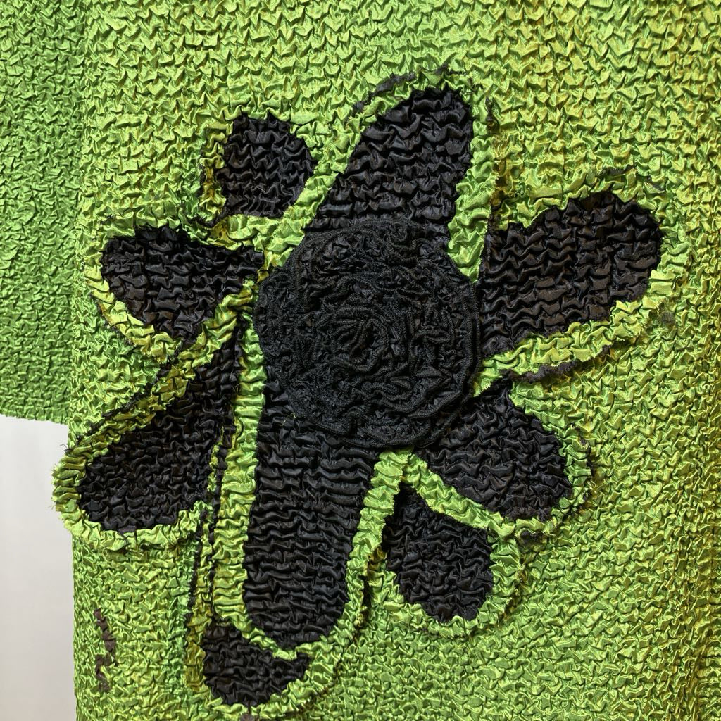 Black flower design on a green textured fabric background