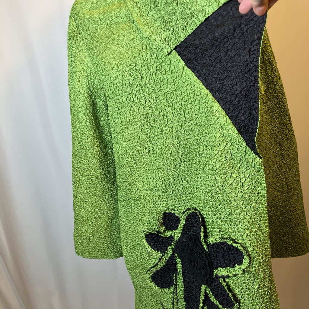 Green krinkle jacket with black geometric design held by a person