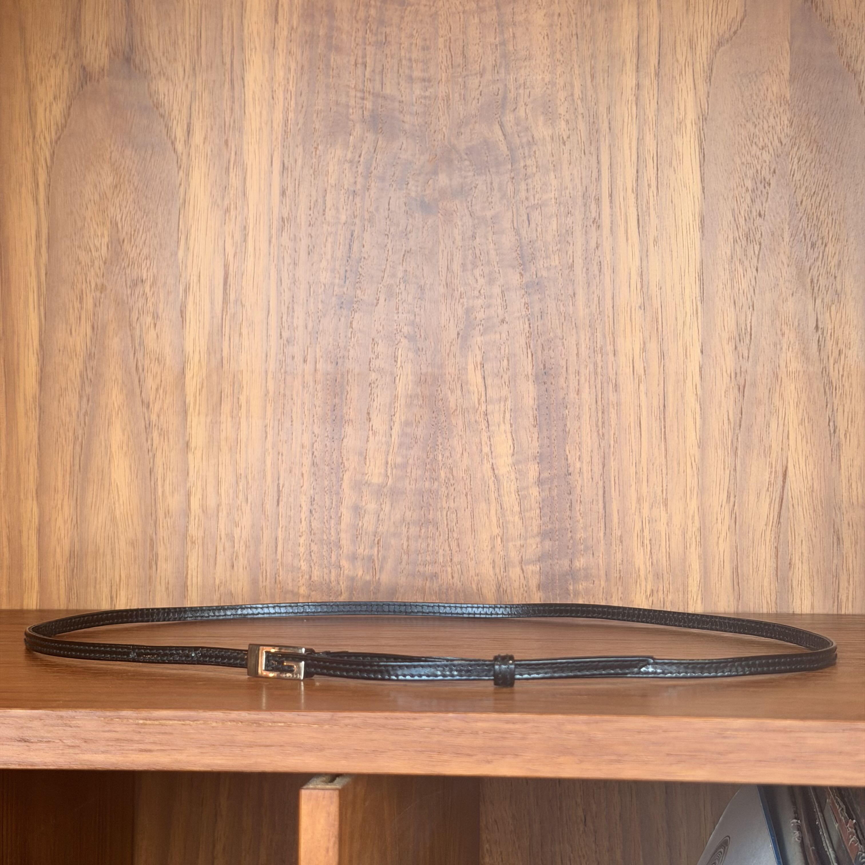 Black leather belt on a wooden surface with a wooden background