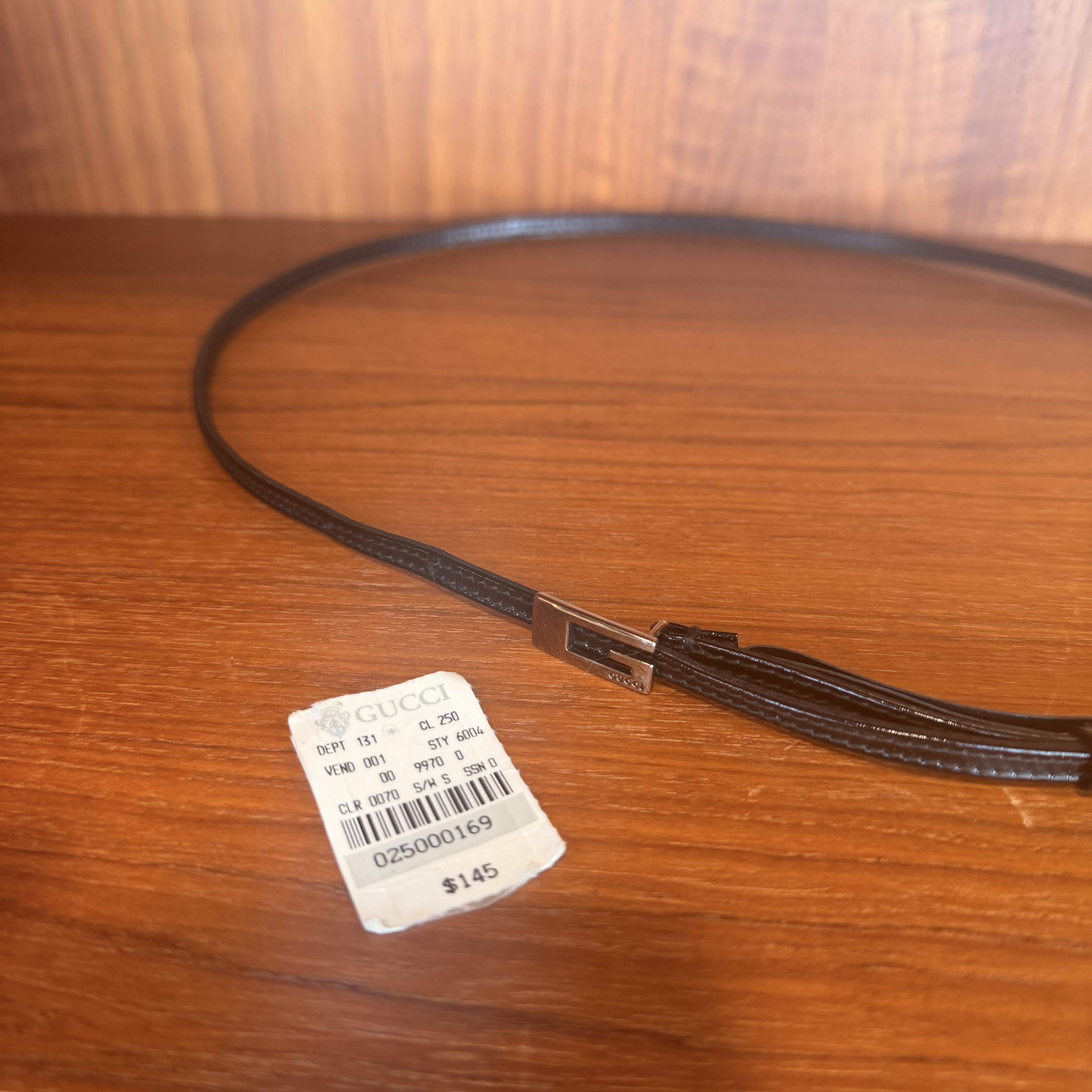 Brown leather belt with a tag on a wooden surface