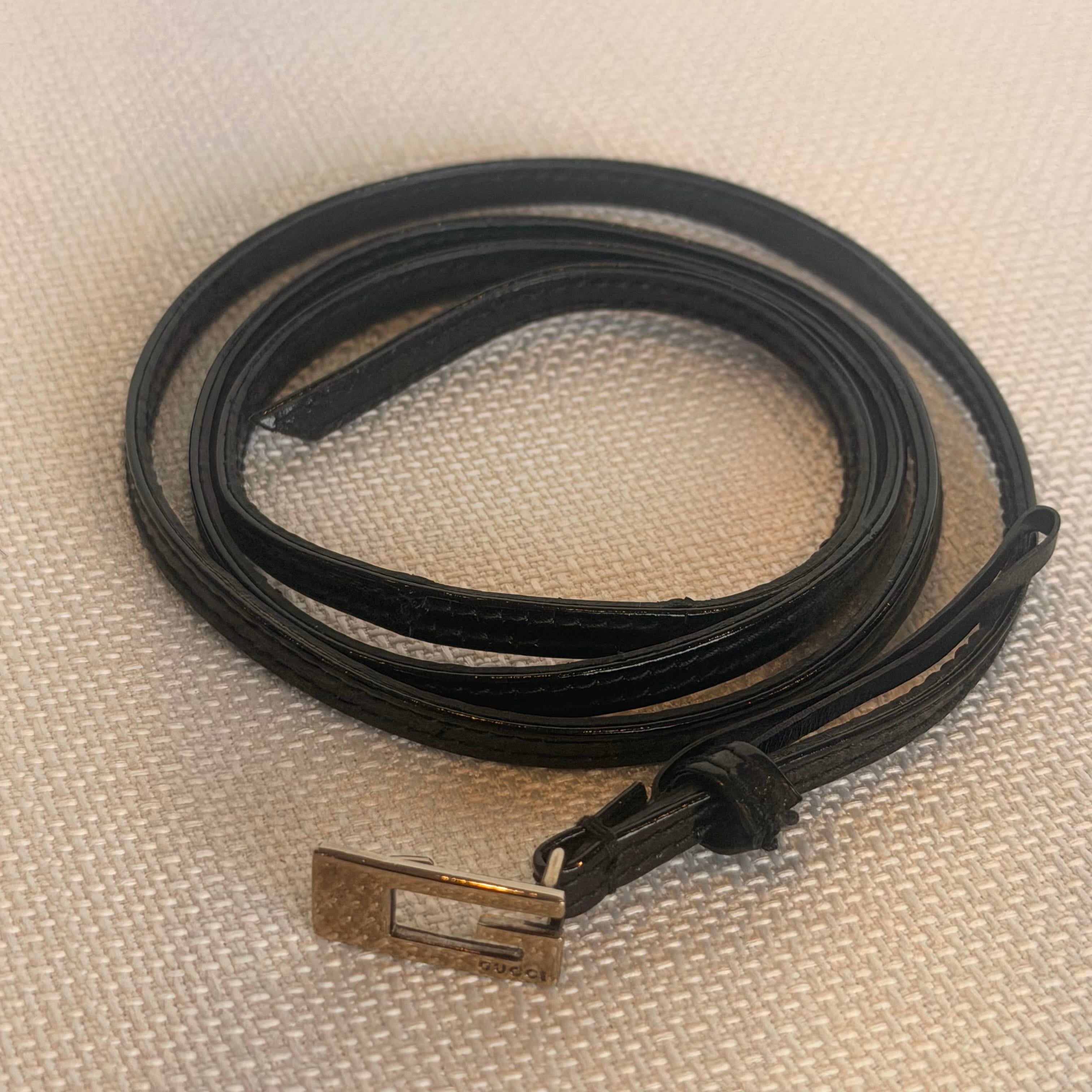 Black leather belt with a metal buckle on a beige fabric background