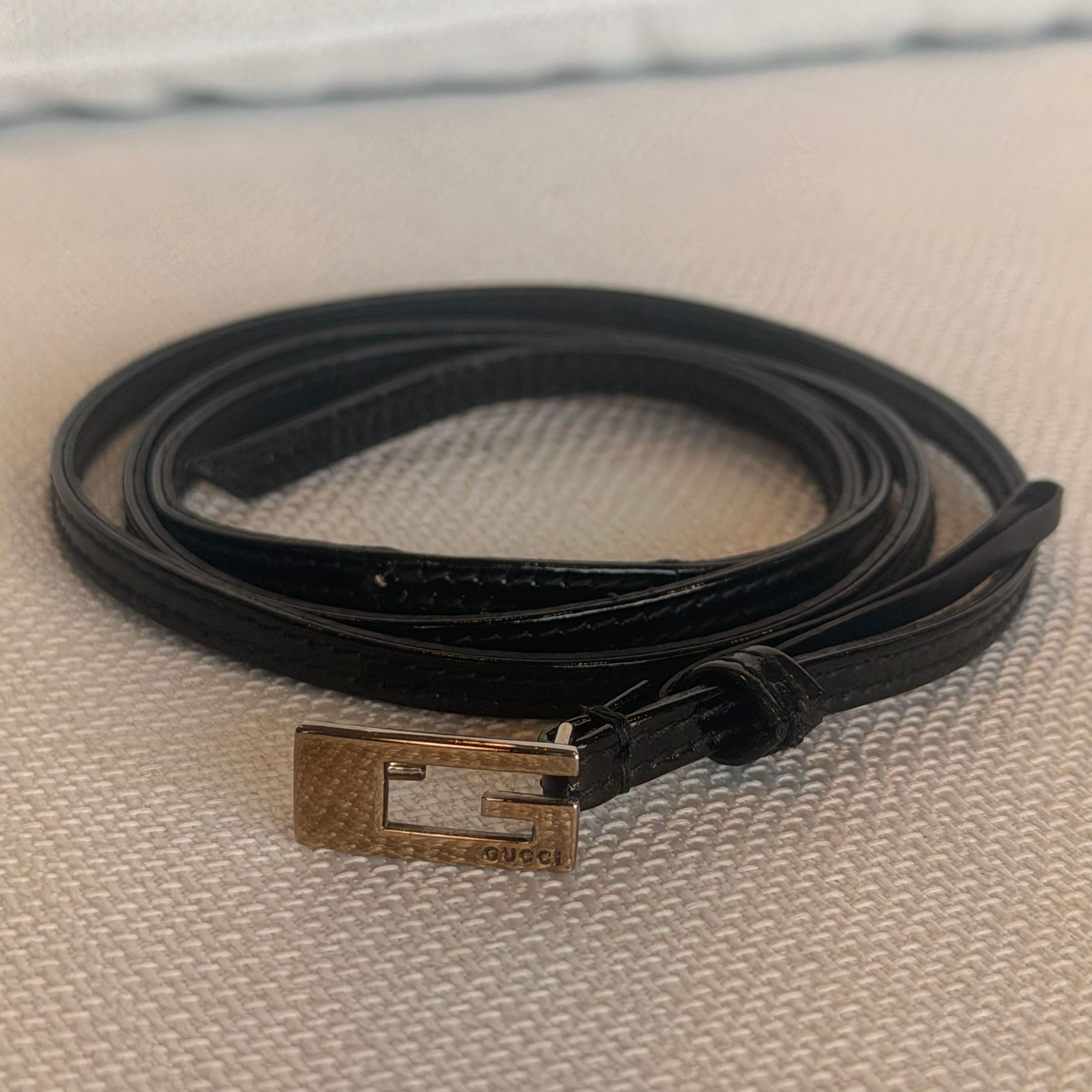 Black leather belt with a metal buckle on a textured surface