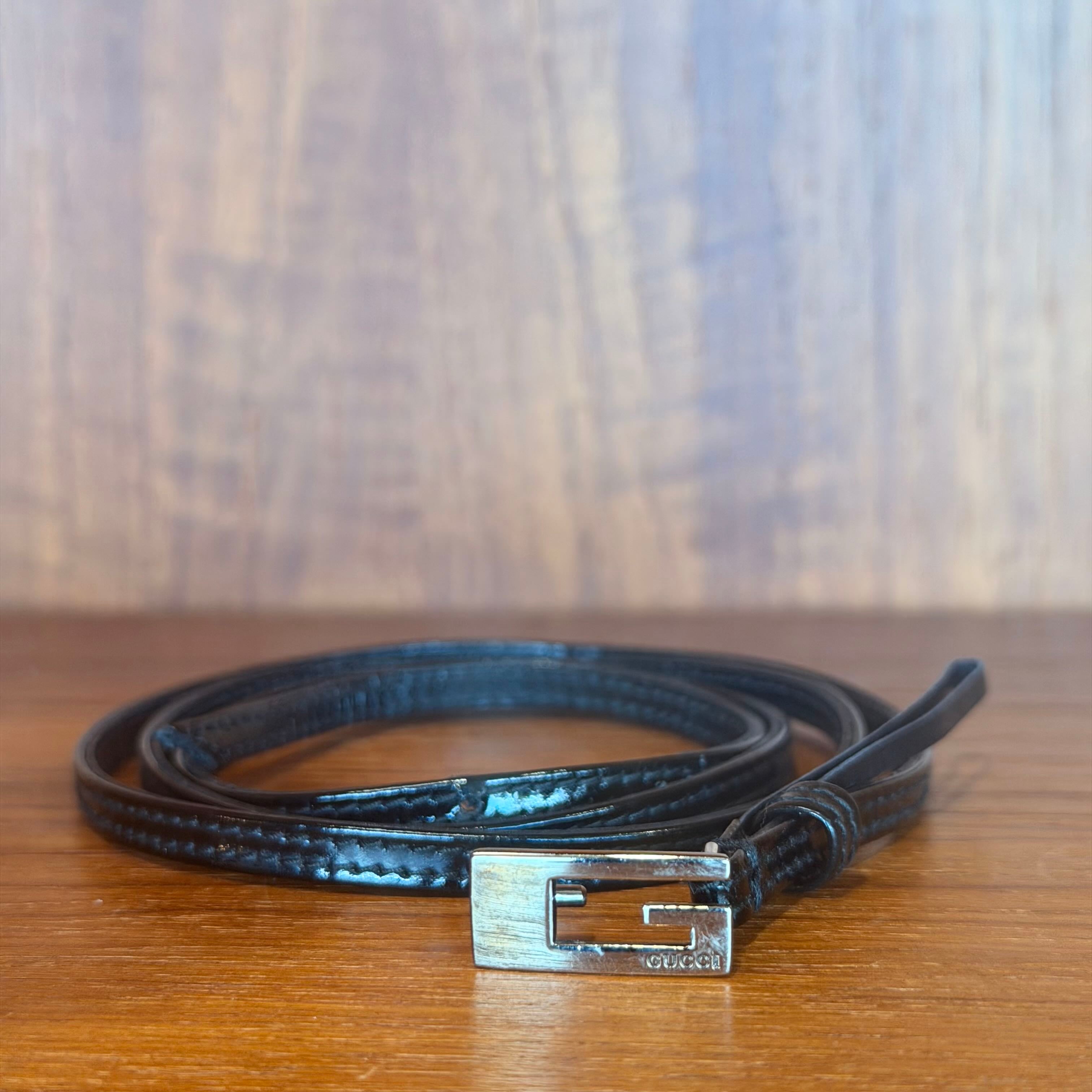 Black leather belt with a silver buckle on a wooden surface