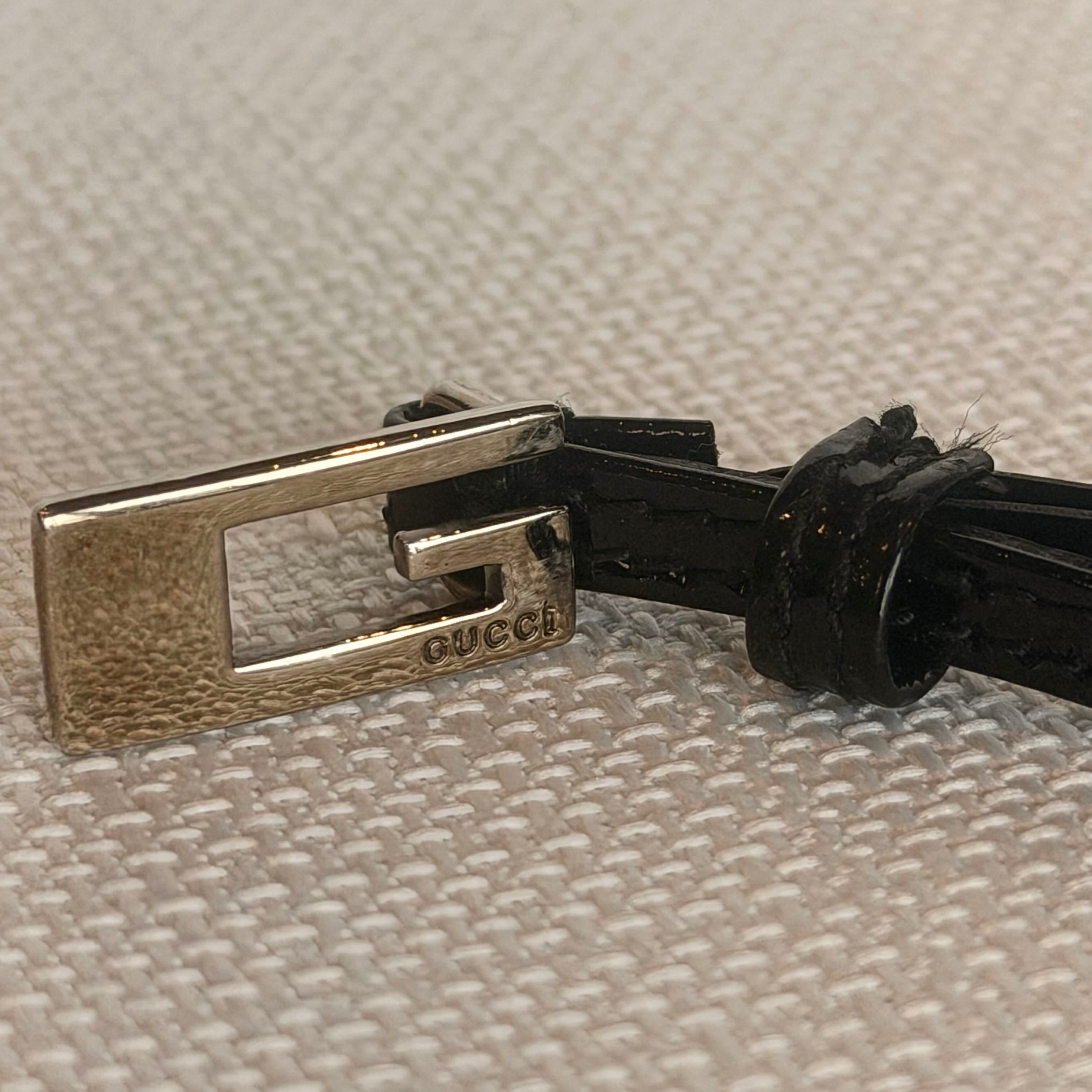 Close-up of a Gucci belt buckle on a textured beige background
