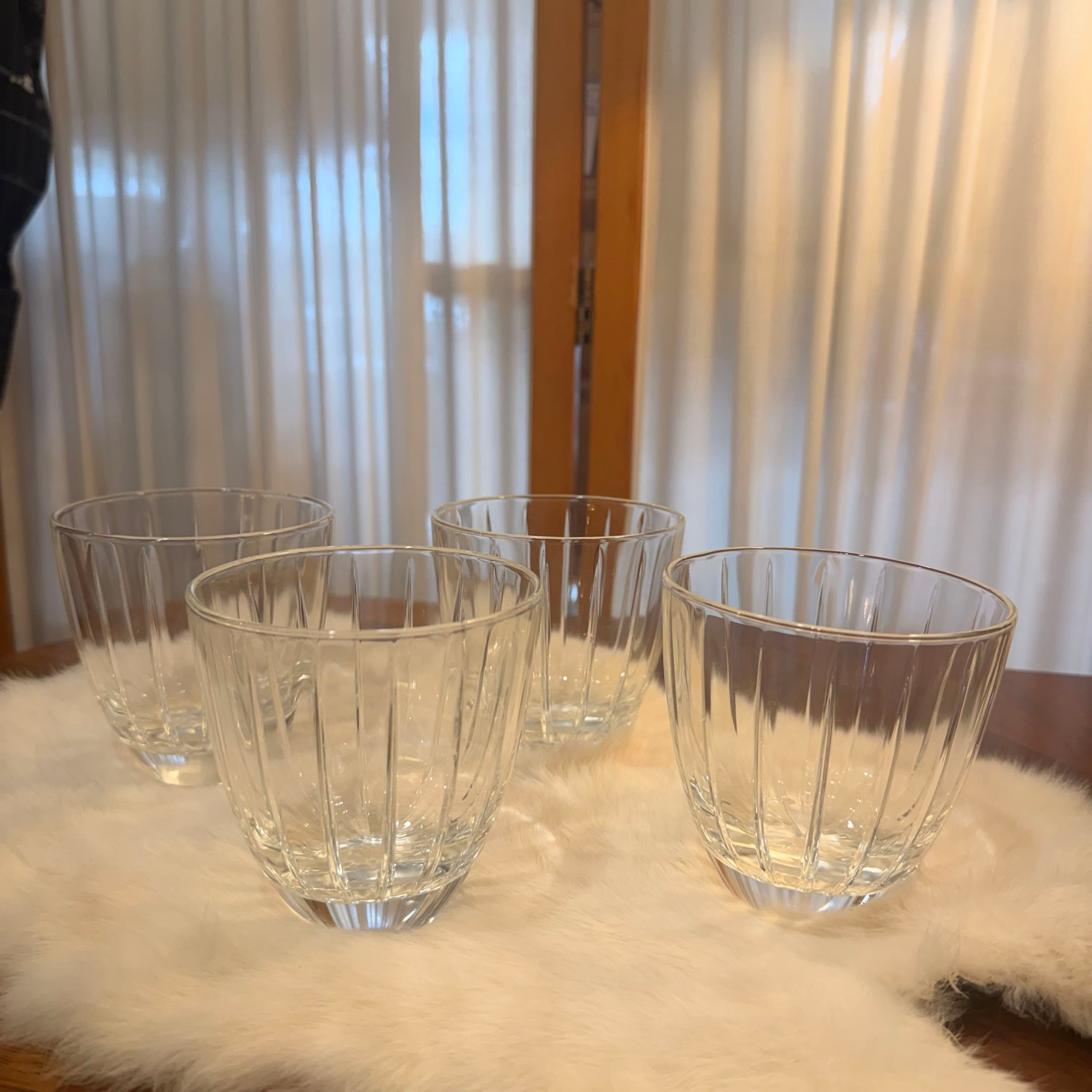 Set of clear glass tumblers on a fur surface with curtains in the background
