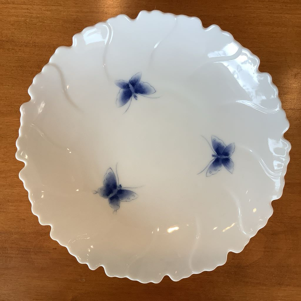 White ceramic bowl with blue butterfly designs on a wooden surface