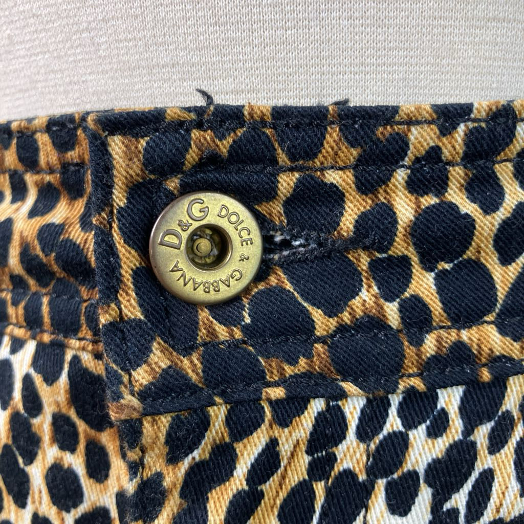 Close-up of a leopard print fabric with a gold button featuring the Dolce & Gabbana logo.