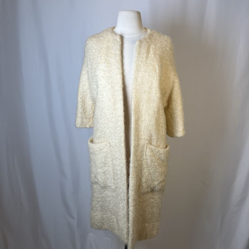 Beige textured long coat on a mannequin against a plain background