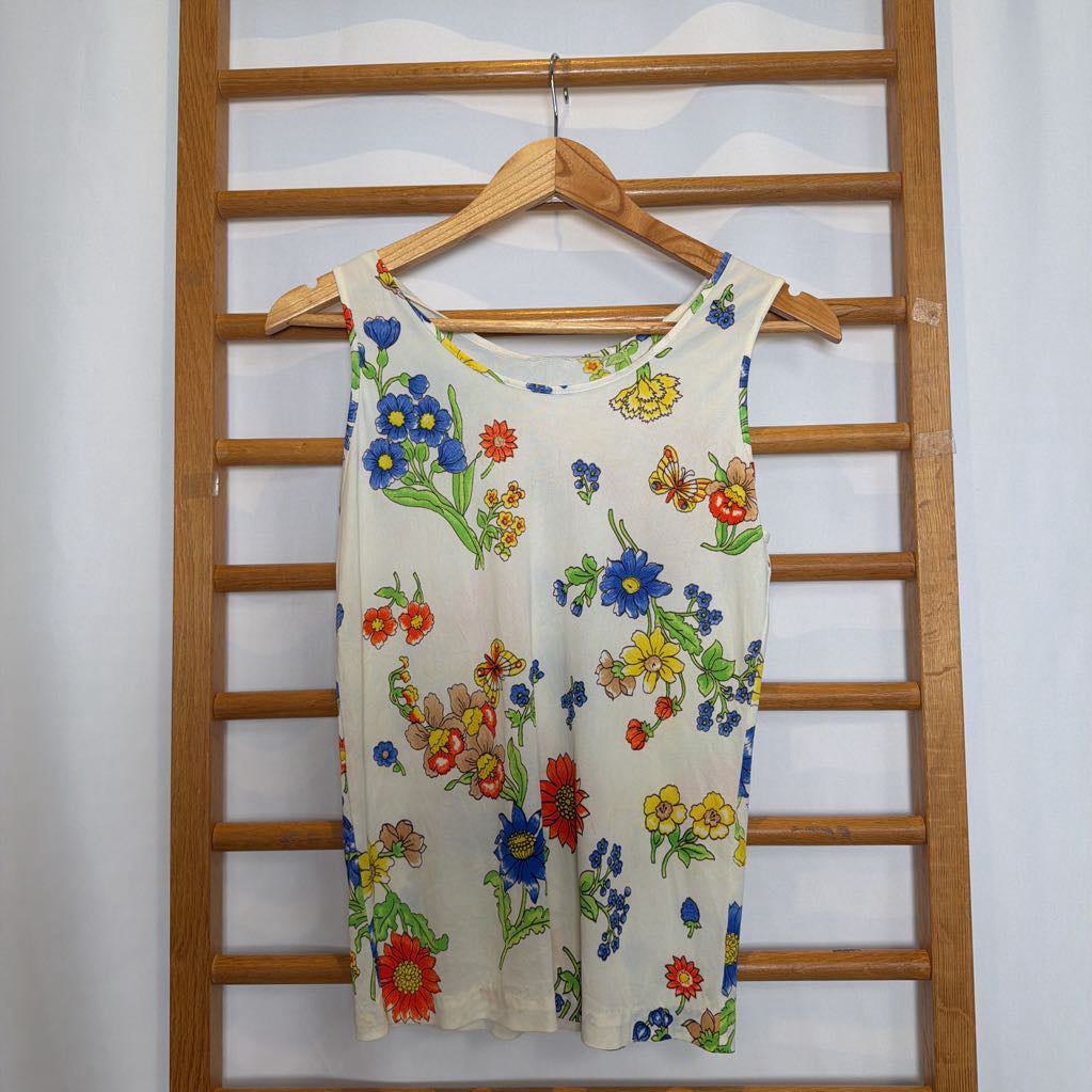 Floral-patterned dress hanging on a wooden rack against a white wall.