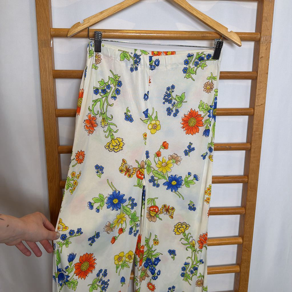 Floral-patterned fabric hanging on a wooden rack against a white wall.