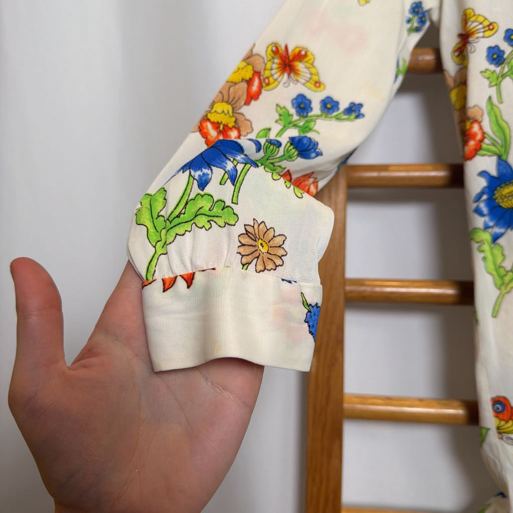 Hand holding a floral-patterned fabric with a wooden chair in the background