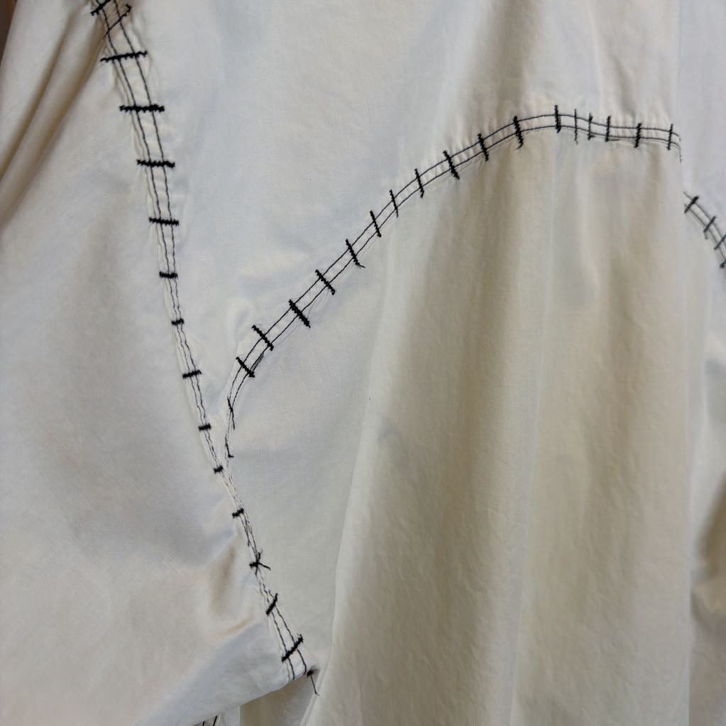 Close-up of a white garment with black stitching details on a white background