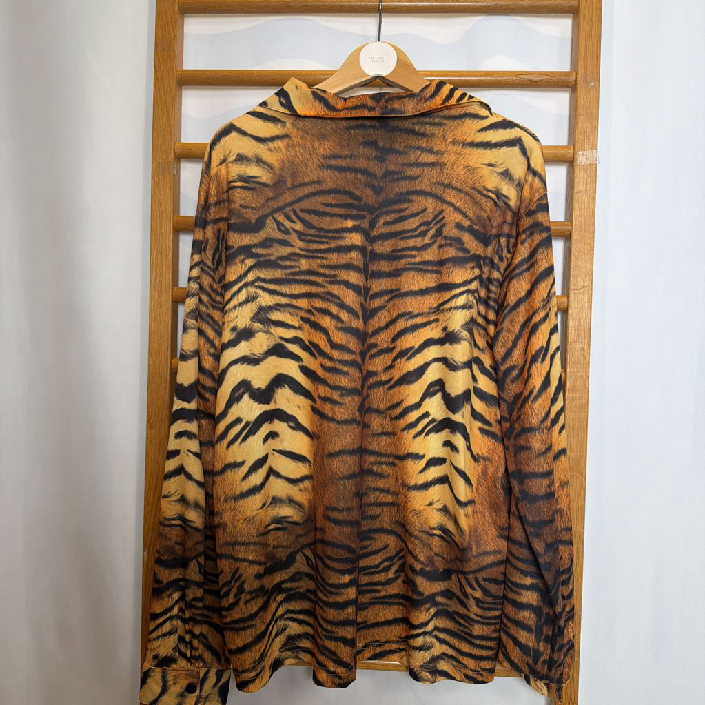 Tiger-patterned garment on a hanger against a wooden panel background