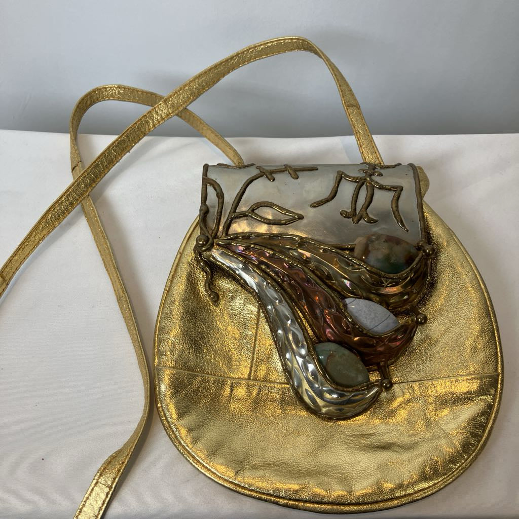 Gold handbag with decorative element on a white surface