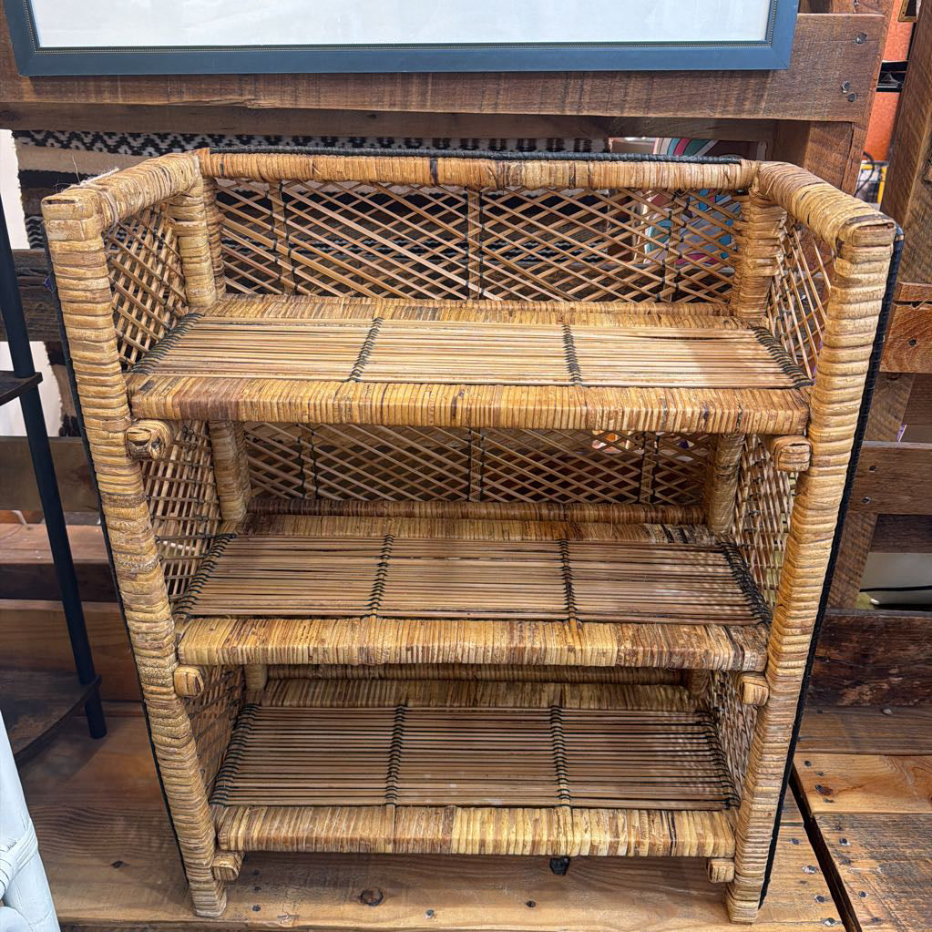 Wicker shelf with three shelves on a wooden floor.