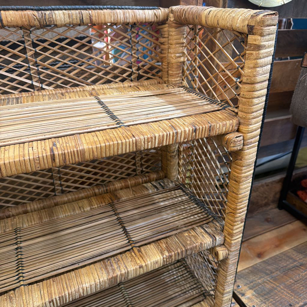 Wicker shelf with three tiers on a wooden floor.