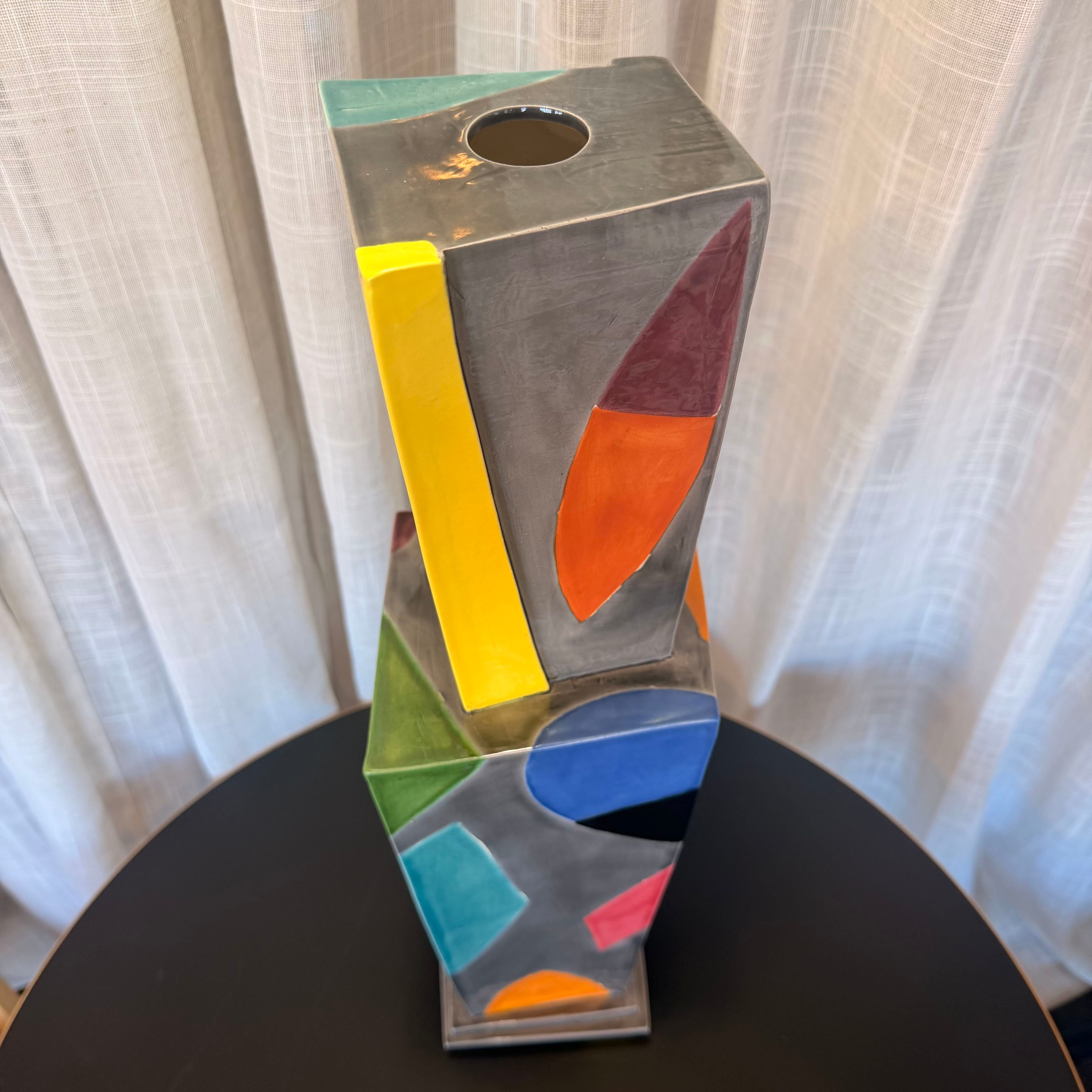 Colorful abstract sculpture on a black surface with a light gray curtain background