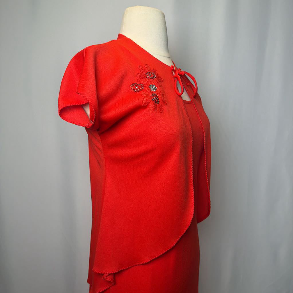 Red dress with embellishments on a mannequin against a plain background