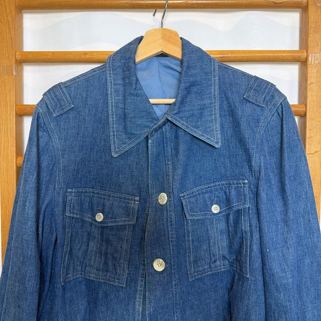 Blue denim jacket on a wooden hanger against a wooden panel background
