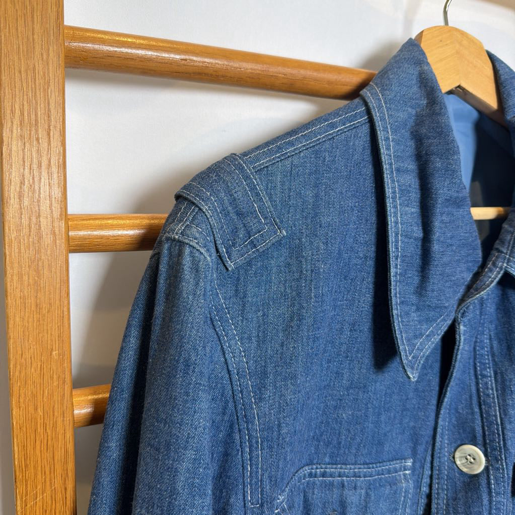 Blue denim jacket hanging on a wooden rack against a white wall