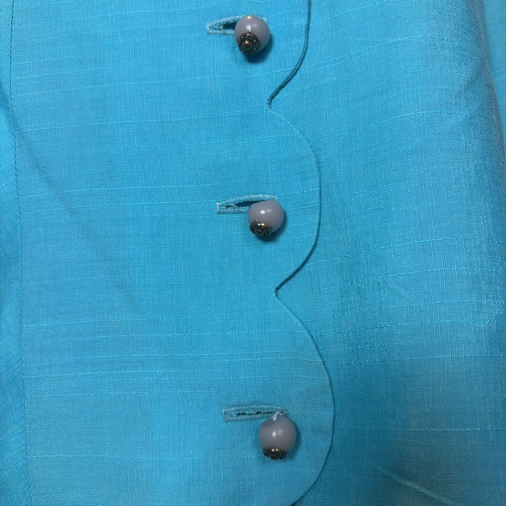 Close-up of a blue fabric with buttons on a plain background