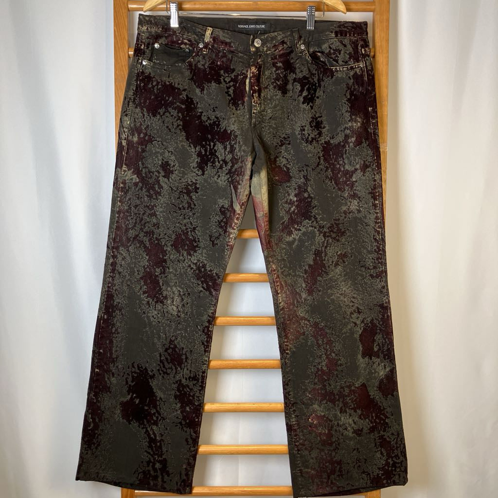 Distressed black jeans hanging on a wooden rack against a white background