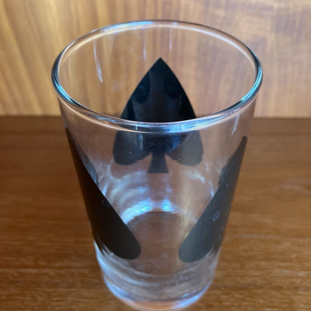 Clear glass with black spade print design on a wooden surface