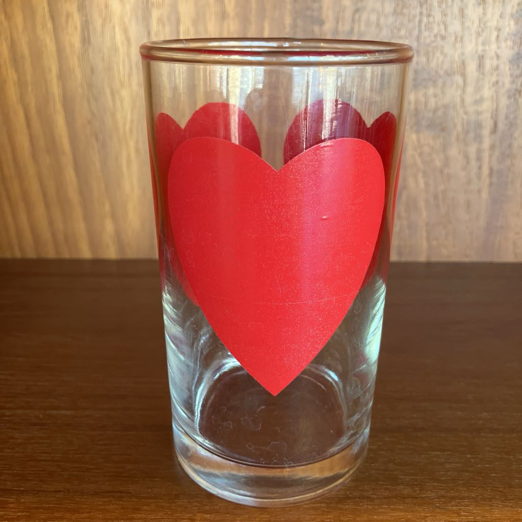 Clear glass with a red heart-shaped design on a wooden surface
