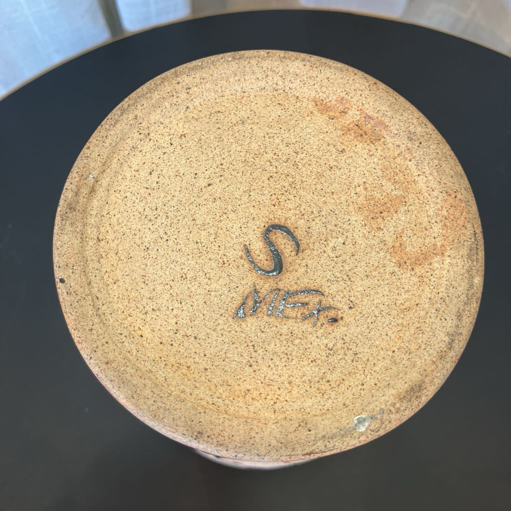 Bottom of a vase with a logo on a black surface