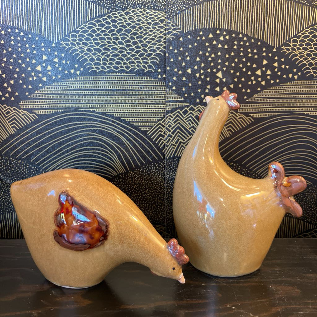 Two ceramic chicken figurines with a decorative background