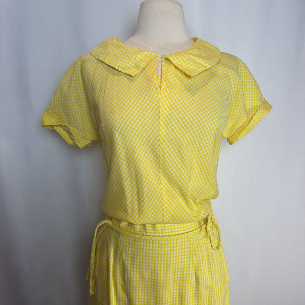 Yellow checkered dress on a mannequin against a plain background