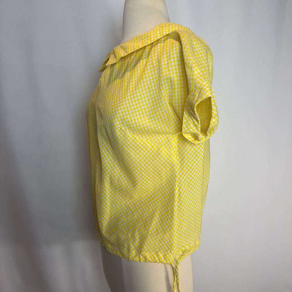 Yellow checkered top on a mannequin against a gray background
