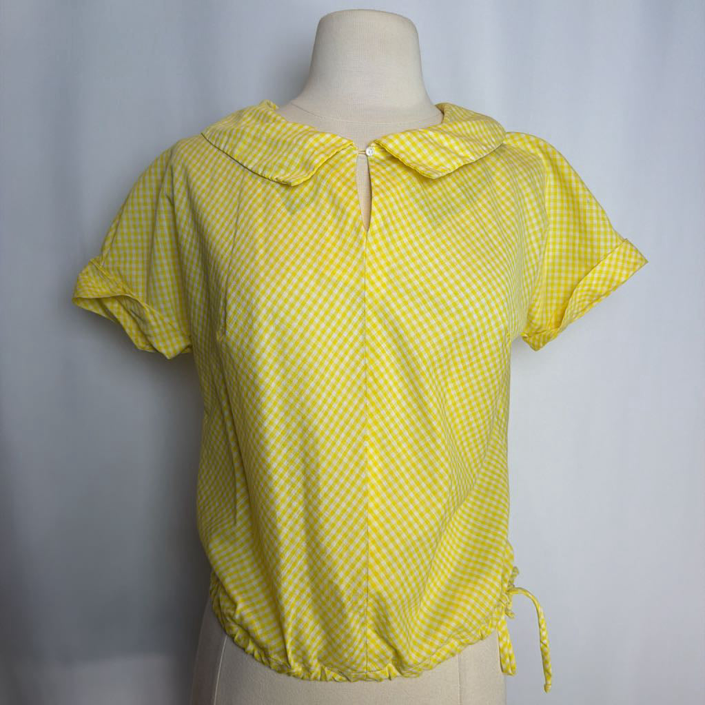 Yellow checkered blouse on a mannequin against a gray background