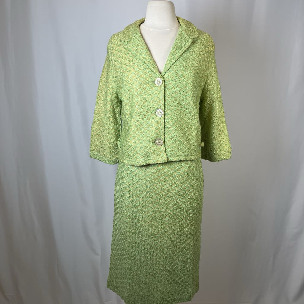 Green textured skirt suit on a mannequin against a plain background