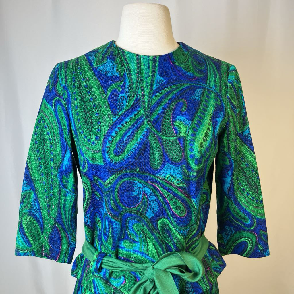 Green and blue patterned dress on a mannequin against a neutral background
