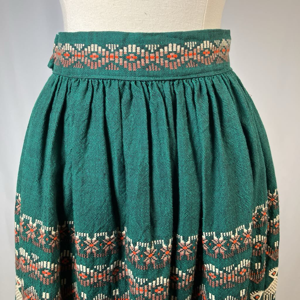 Green skirt with patterned waistband and hem on a mannequin against a plain background