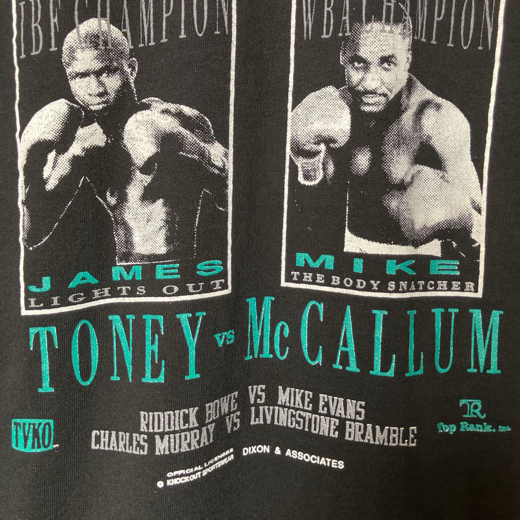 Close-up of a black graphic print featuring two boxer portraits with text reading 'Toney vs McCallum' and fight-related wording in white and teal.