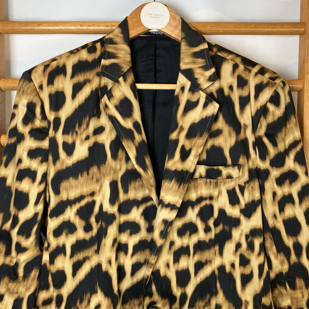 Leopard print blazer on a wooden hanger against a white wall.
